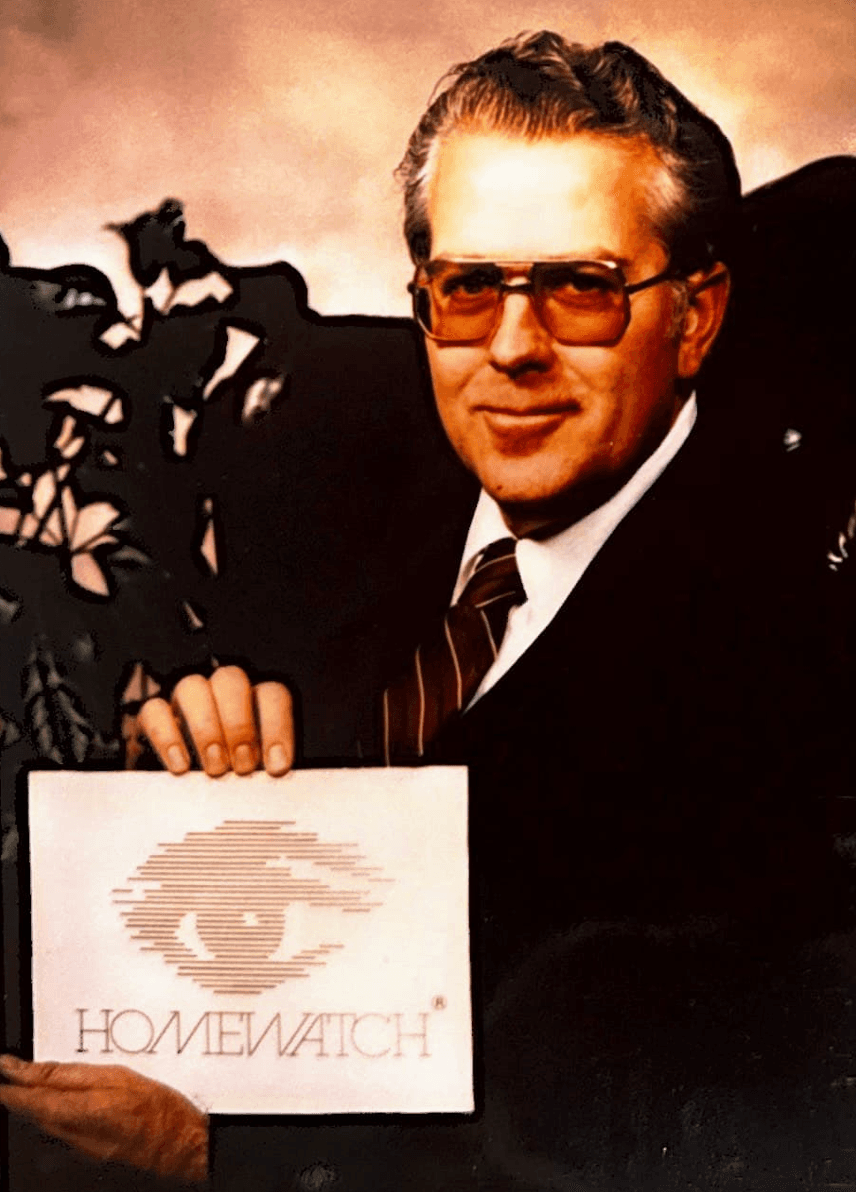 Paul Sauer, founder of Homewatch CareGivers, holding the original Homewatch sign in 1980